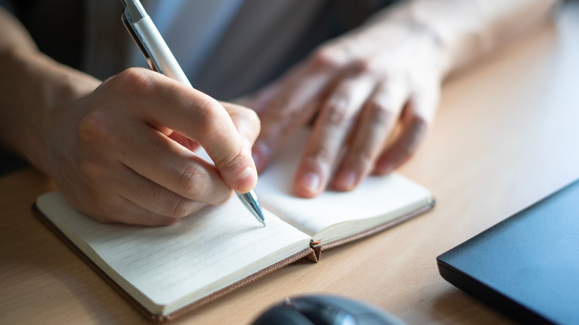 Close-up Man hand writes in notebook